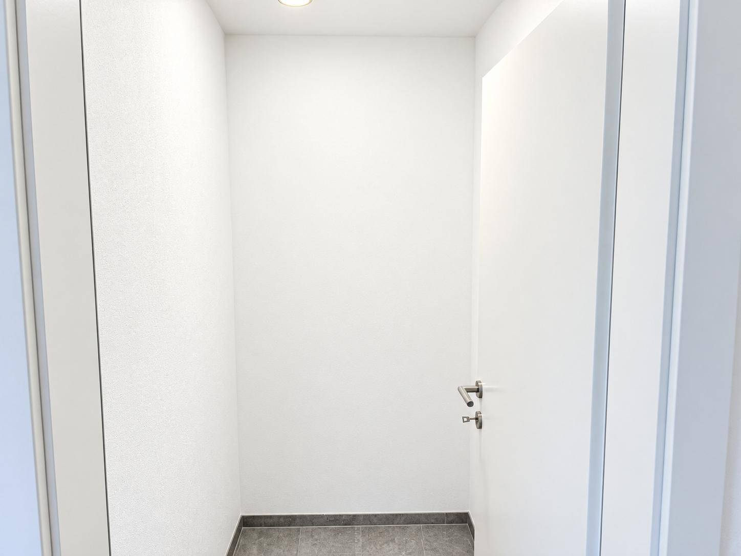 Kleiner Eingangsbereich mit Fliesenboden und weiß gestrichenen Wänden.