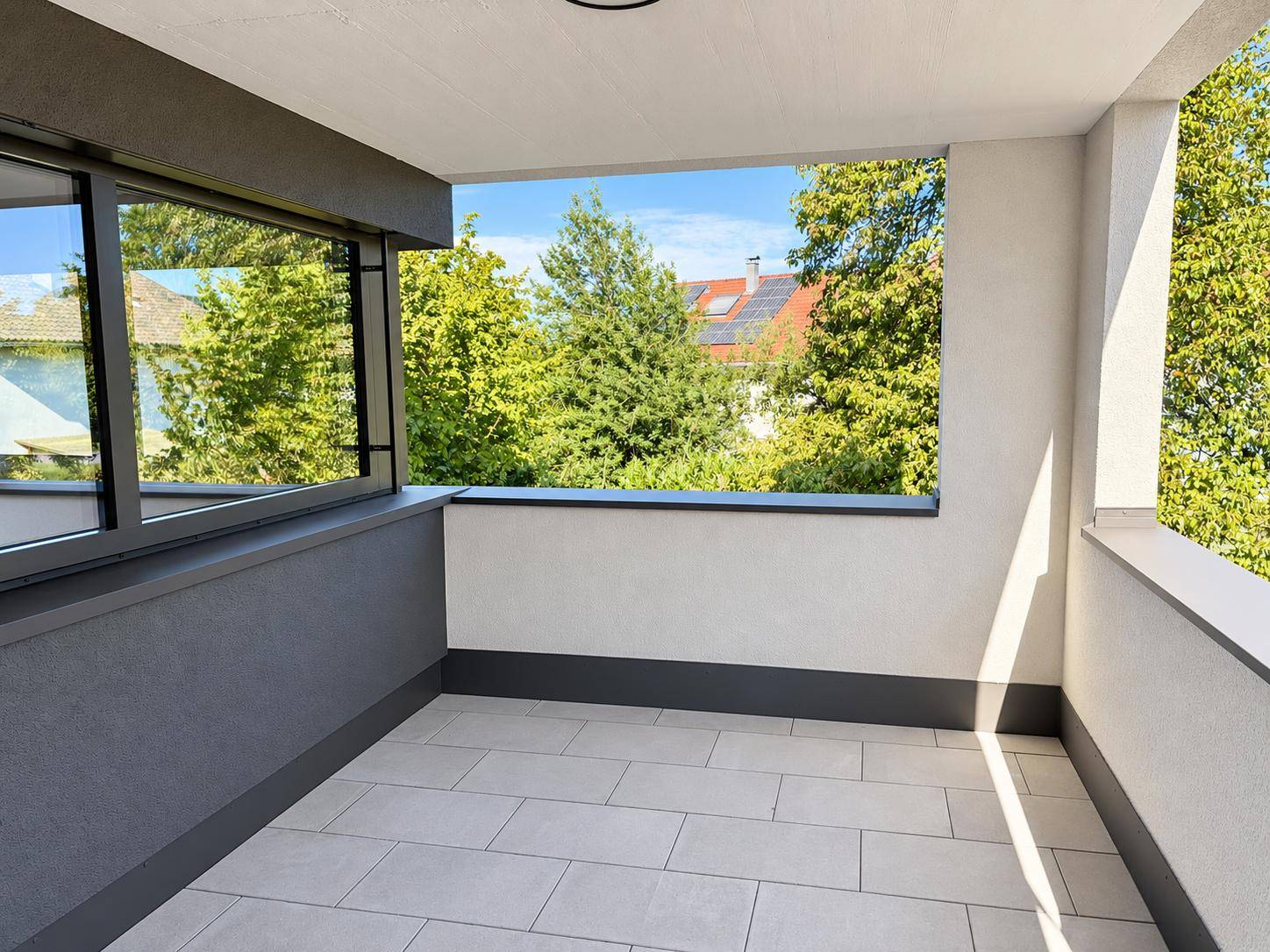 Geräumige Loggia mit Fliesenboden und Blick ins Grüne, ideal zum Entspannen.