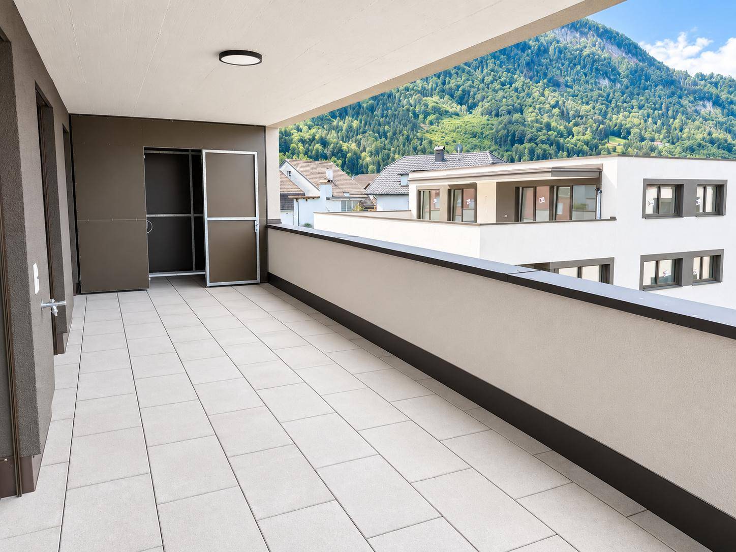 Geräumiger Balkon mit Fliesenboden und beeindruckendem Bergblick, inklusive Stauraum.