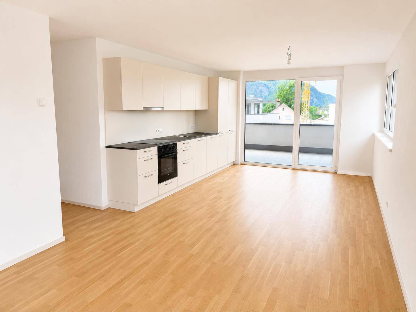 Lichtdurchfluteter offener Wohnbereich mit Zugang zur Terrasse und Bergblick, ausgestattet mit Laminatboden.