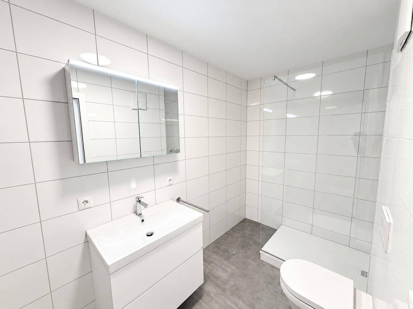 Modernes Badezimmer mit weißen Fliesen, ebenerdiger Dusche, Waschtisch und Spiegelschrank.