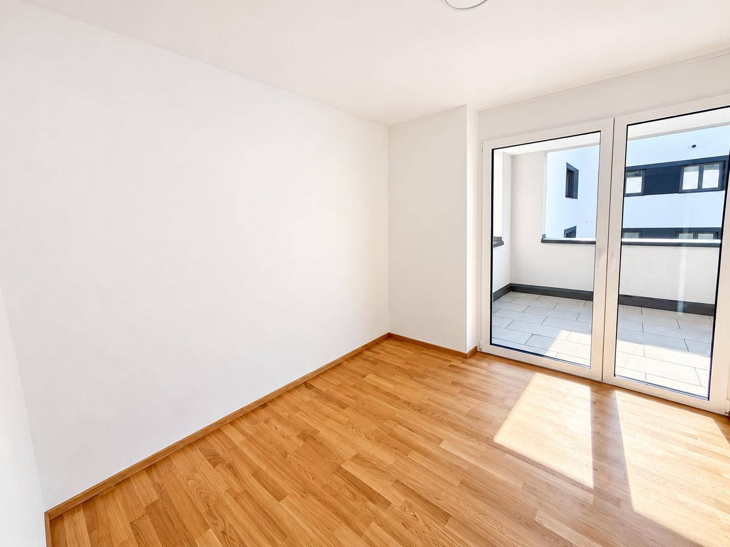 Geräumiges Zimmer mit viel Tageslicht und Schiebetüren, die auf den Außenbereich führen.