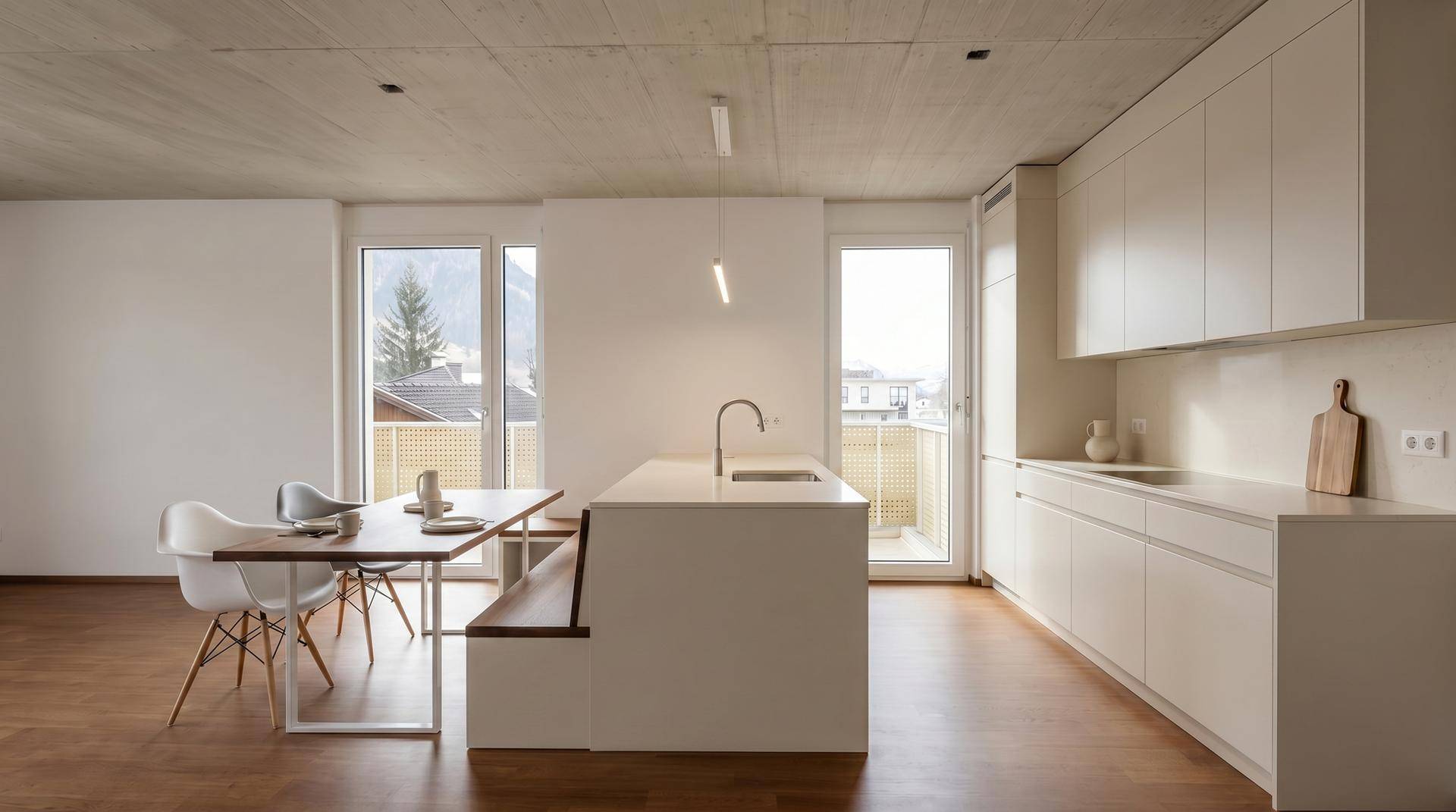 Moderne Einbauküche mit Kochinsel und Essbereich, Holzboden und Balkonzugang.