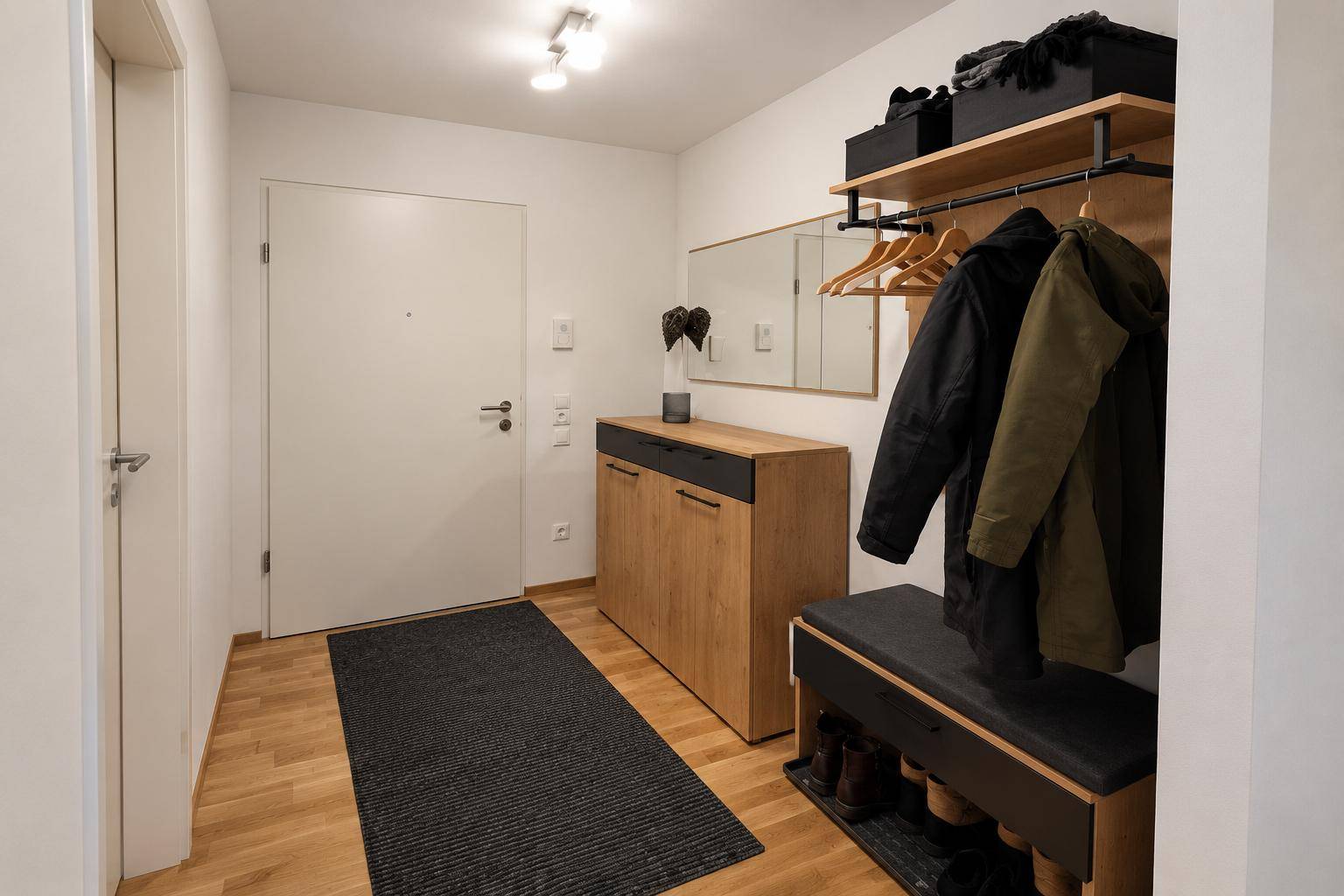 Heller Eingangsbereich mit modernem Garderobenmöbel, Spiegel und Holzfußboden.