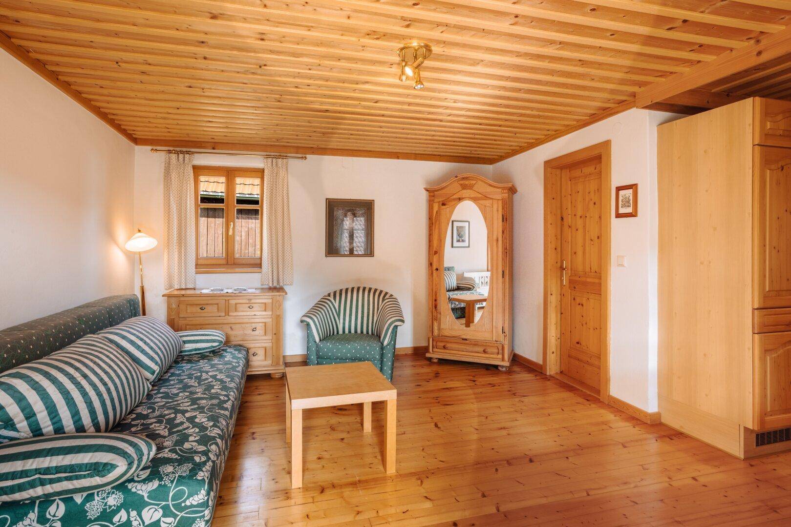 Weiterer Blick ins Wohn- oder Gästezimmer mit Holzschrank, Spiegel und traditioneller Einrichtung.