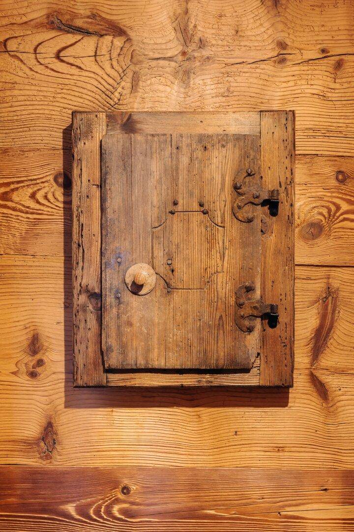 Rustikale Holztür oder Luke mit schmiedeeisernen Beschlägen in einer Holzwand.