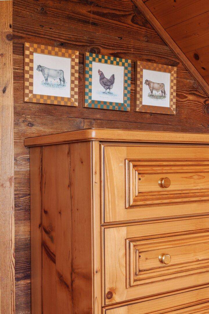 Hölzerne Kommode mit traditionellen Bildern von Tieren an einer Holzwand.