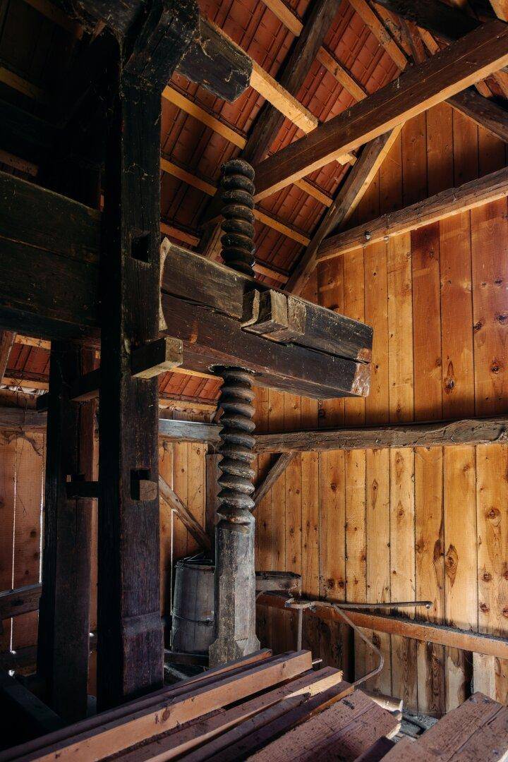 Massive Holzkonstruktion mit großen Balken und Spindel in einem rustikalen Dachboden oder Scheune.