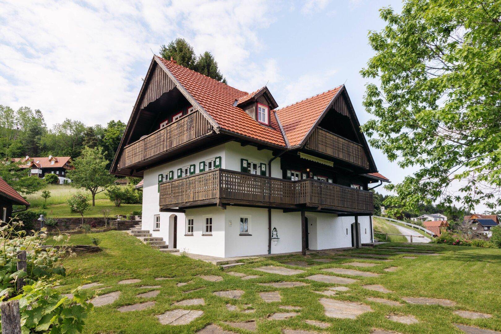 Seitenansicht des Hauses mit mehreren Balkonen und einem dekorativen Steinweg auf dem Rasen.