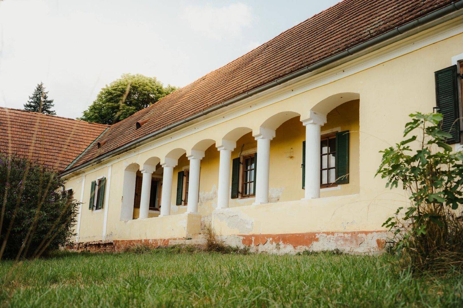 Historische Fassade mit einer beeindruckenden Säulenreihe und traditionellen Fensterläden.