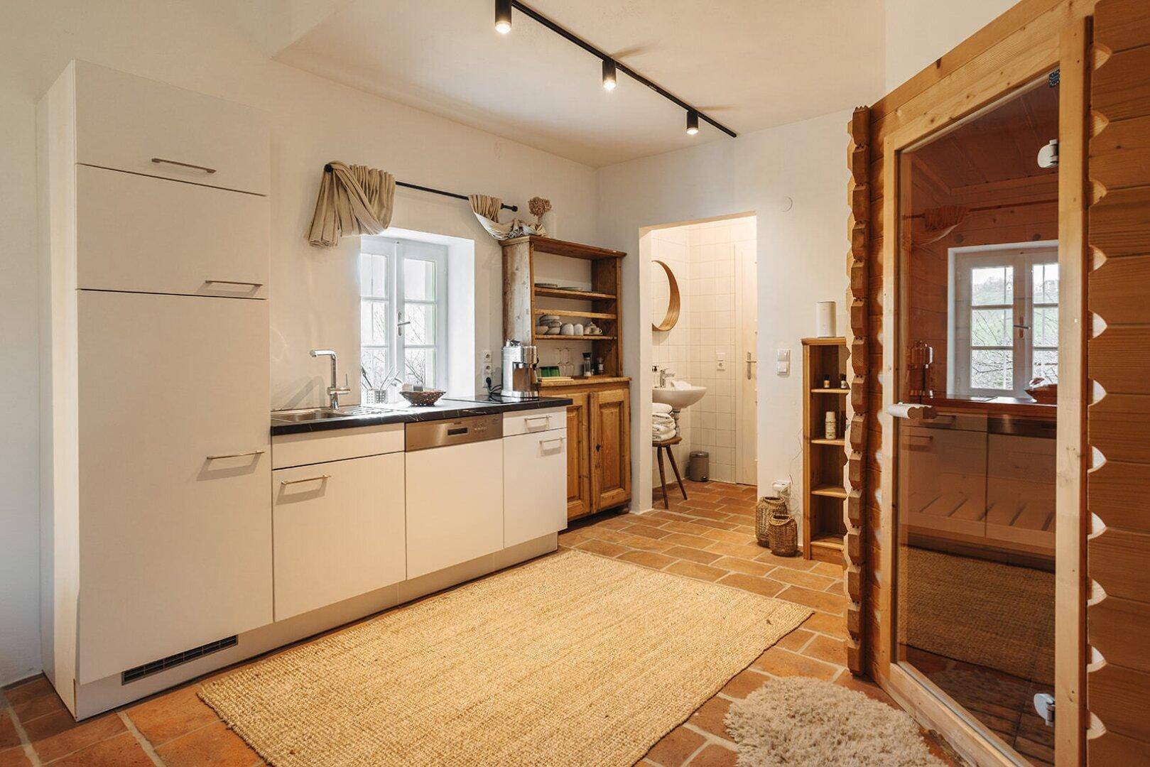Kleine Küchenzeile mit modernen Schränken und angrenzender Sauna in rustikalem Ambiente.