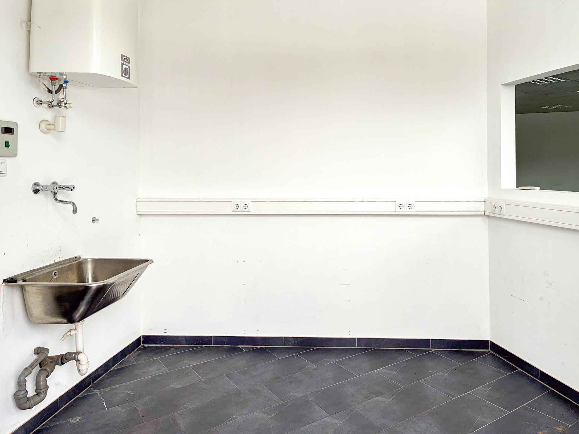 Hauswirtschaftsraum oder kleine Teeküche mit Edelstahlspüle, Warmwasserbereiter und praktischer Steckdosenleiste.