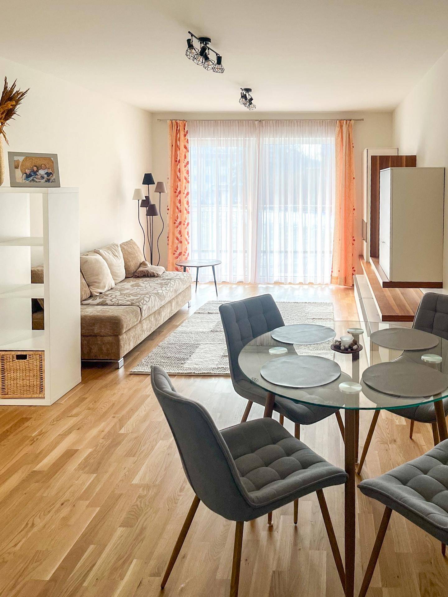 Heller Wohn-Essbereich mit Holzboden, gemütlichem Sofa und modernem Esstisch am Fenster.