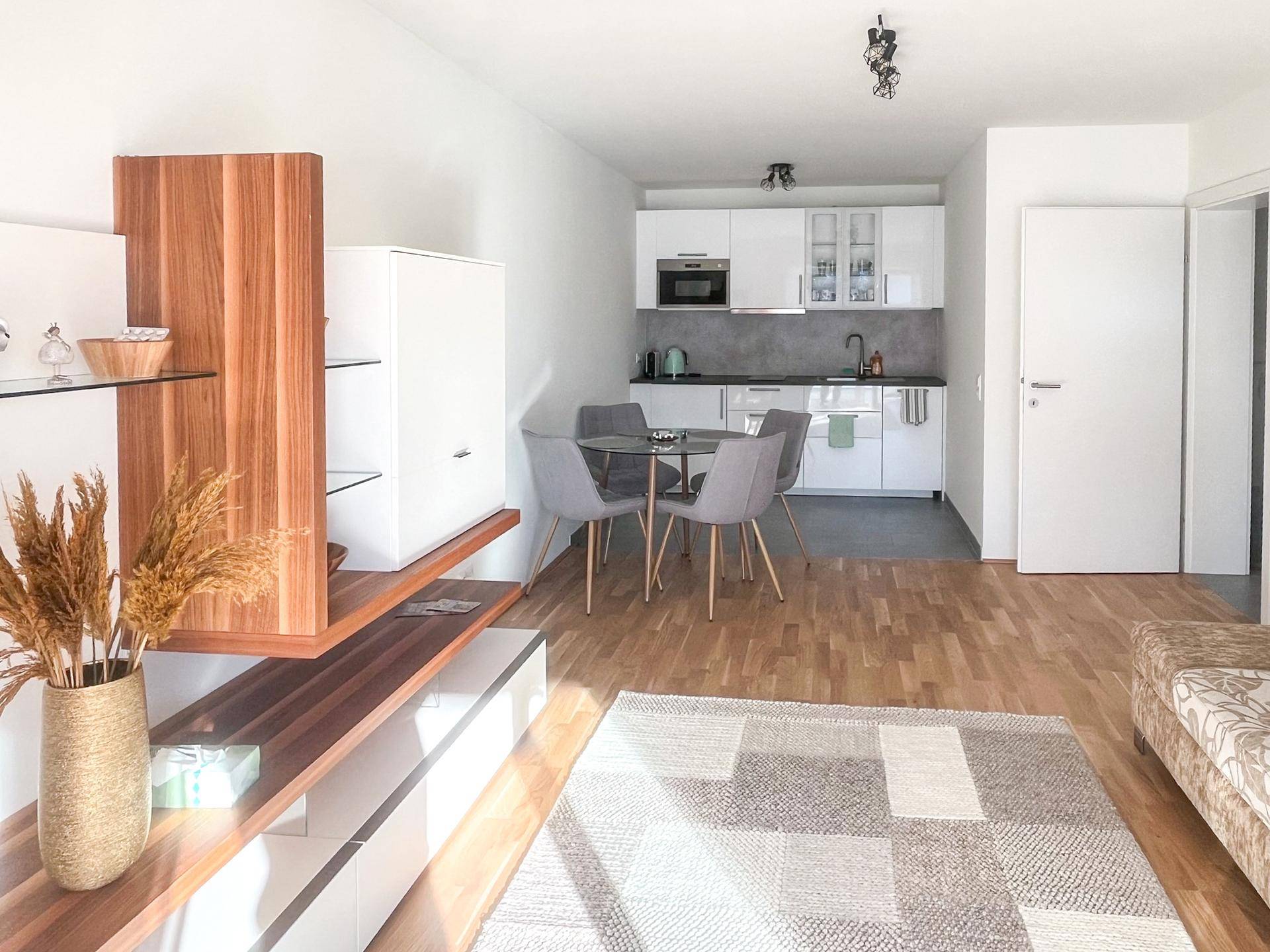 Offener Wohnbereich mit integrierter Küche, Esstisch und Holzboden, hell und modern gestaltet.