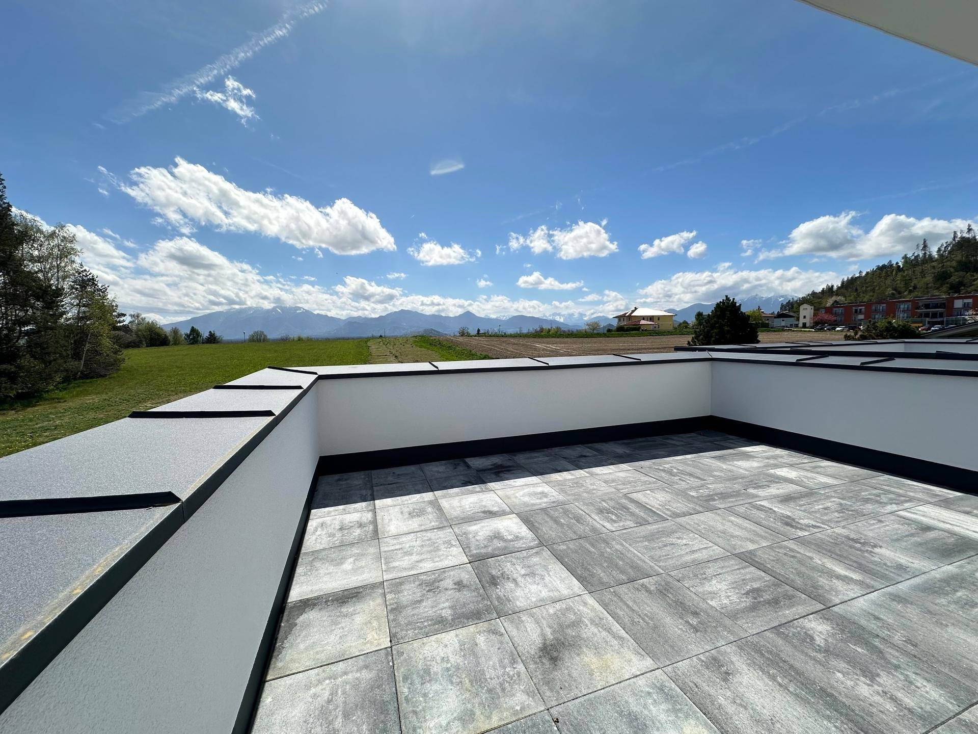 Geräumige Dachterrasse mit Fliesenboden und weitem Blick auf die umliegende Berglandschaft.
