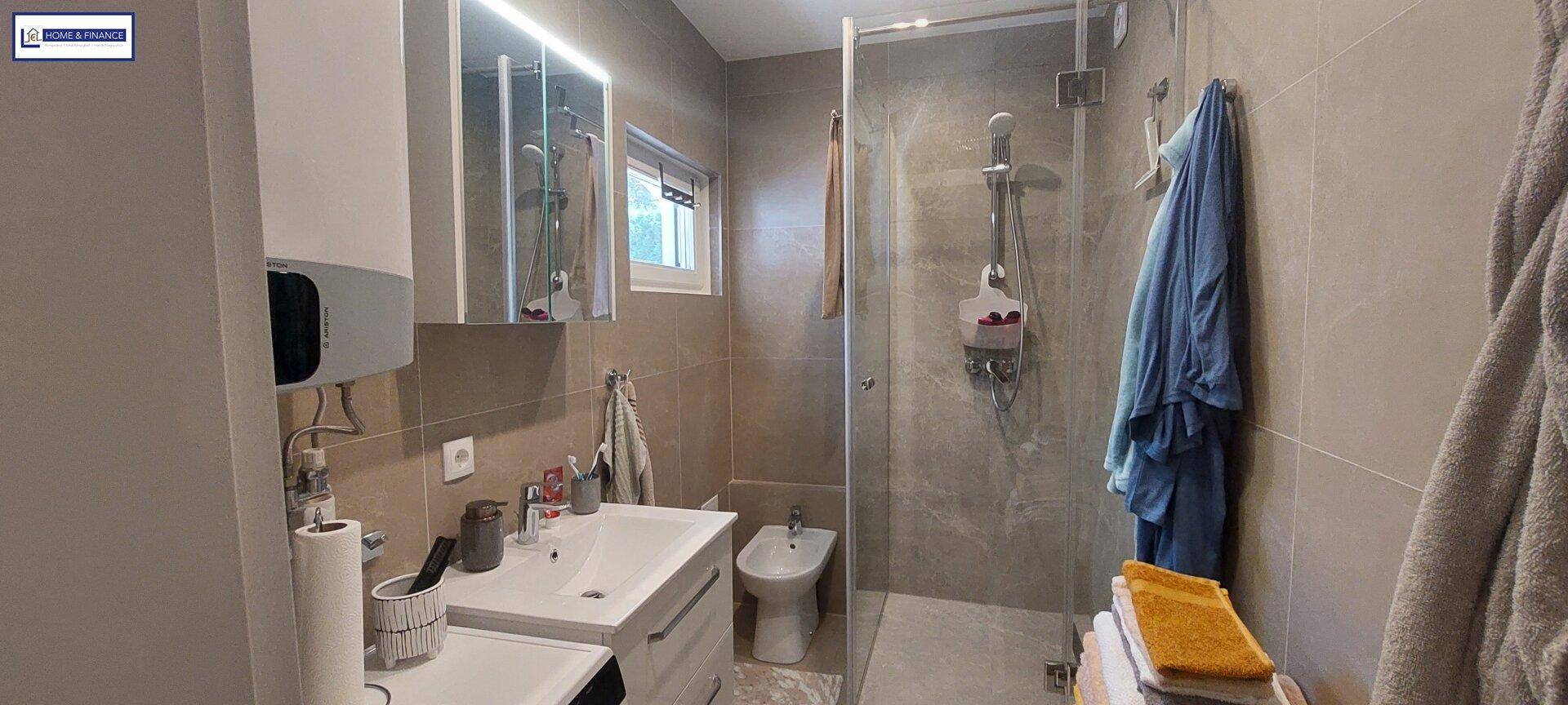 Modernes Badezimmer mit ebenerdiger Dusche, Einzelwaschbecken, Bidet und Fenster.