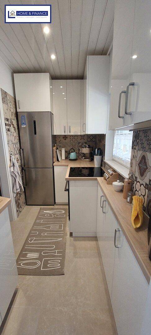 Moderne Küche mit weißen Schränken, Holzarbeitsplatten und gemusterten Fliesen als Spritzschutz.