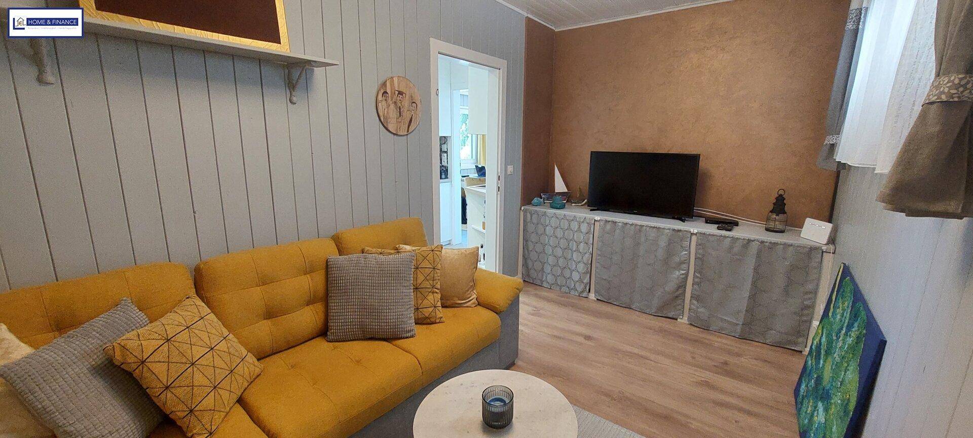 Helles Wohnzimmer mit gelbem Ecksofa, Couchtisch und Holzfußboden.
