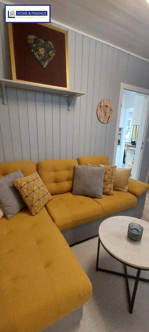 Detailansicht des gelben Ecksofas mit Kissen und einem runden Couchtisch im Wohnzimmer.