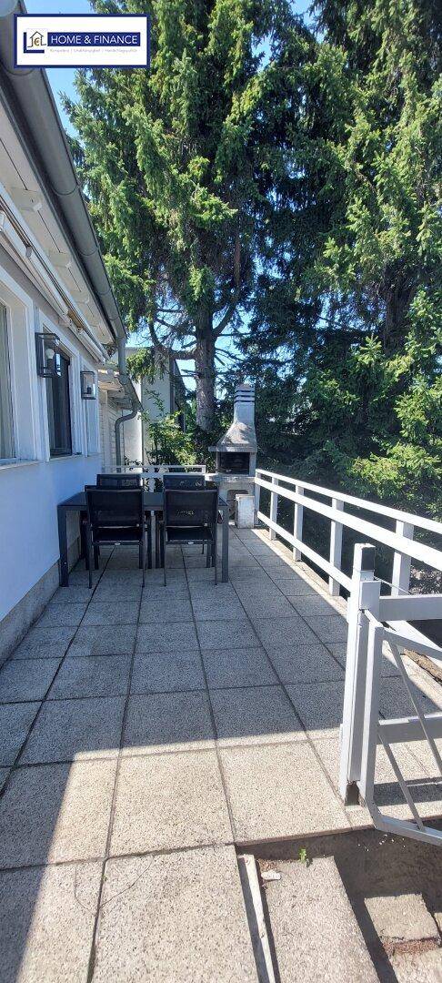 Gemütliche Terrasse mit Essbereich und fest installiertem Grill, ideal für Mahlzeiten im Freien.