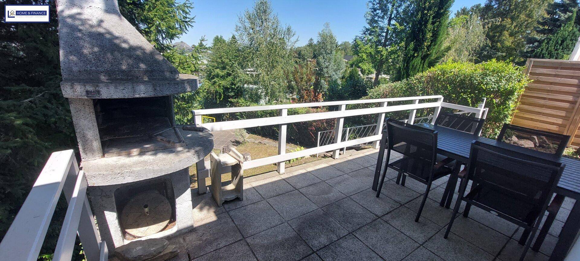 Detailansicht des gemauerten Grills auf der Terrasse, umgeben von Gartenmöbeln.