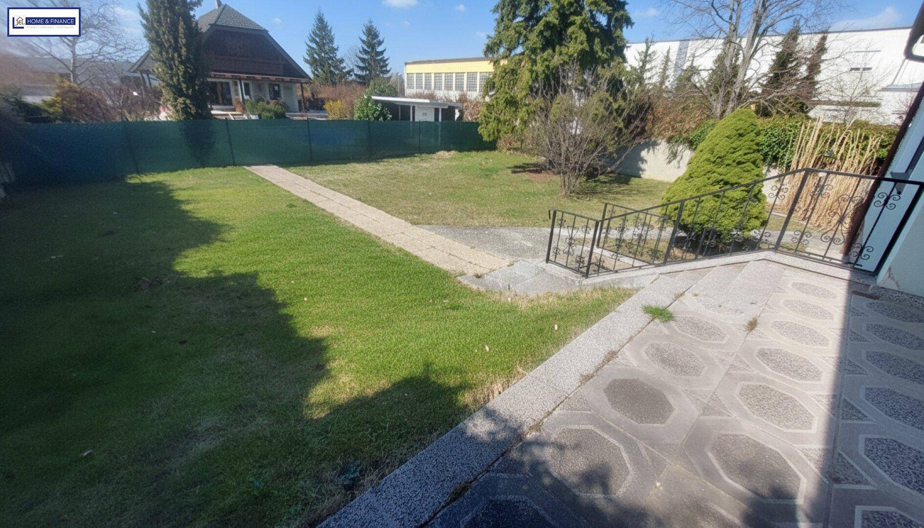 Gepflasterter Bereich neben dem Haus mit Blick auf den weitläufigen Garten und die Umgebung.