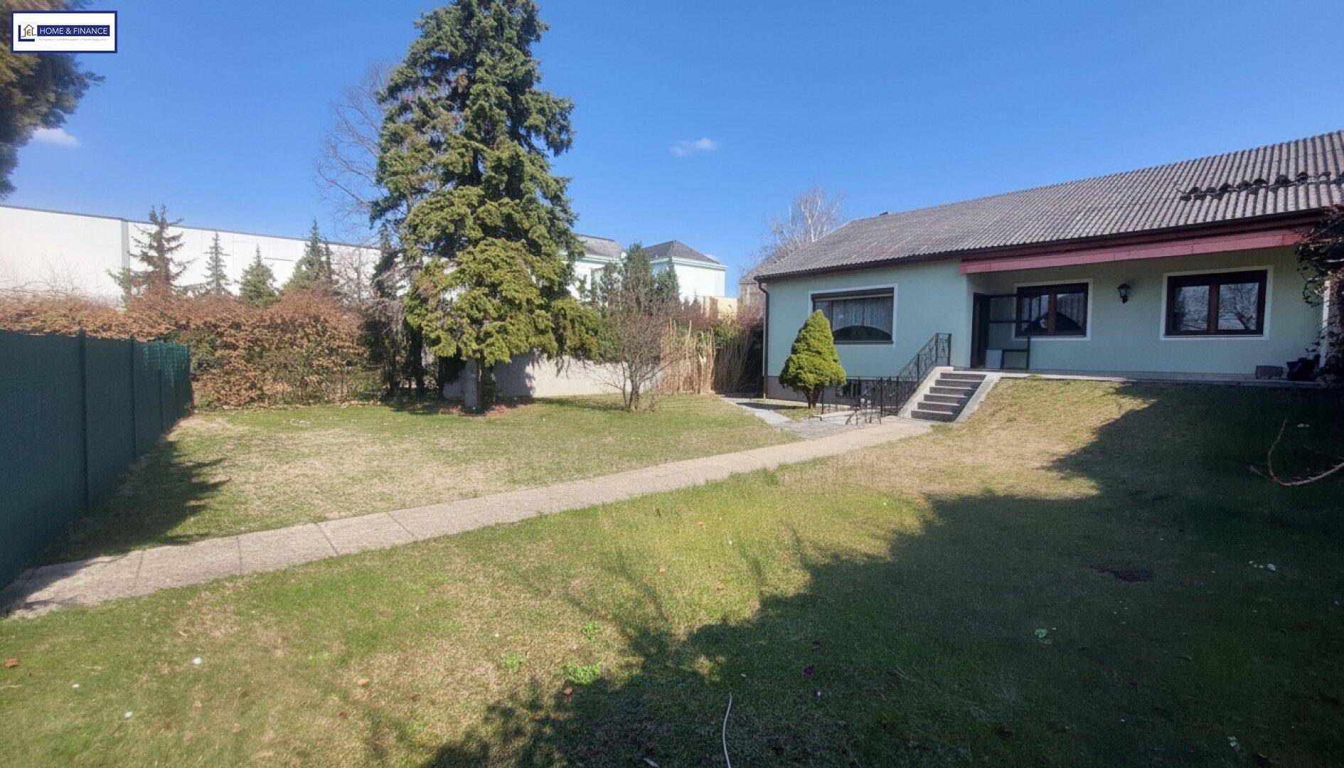 Weitläufiger Gartenbereich mit Rasenfläche, hohen Bäumen und Blick auf das Einfamilienhaus.