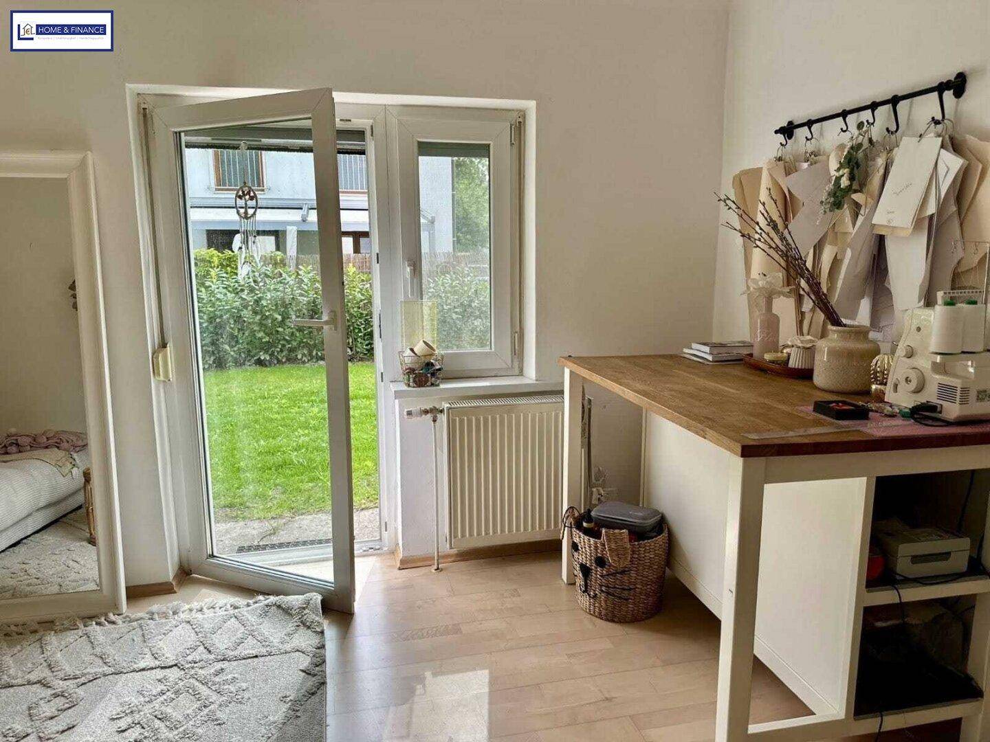 Heller Arbeitsbereich mit Holztisch, Heizung und direktem Zugang zum Garten.