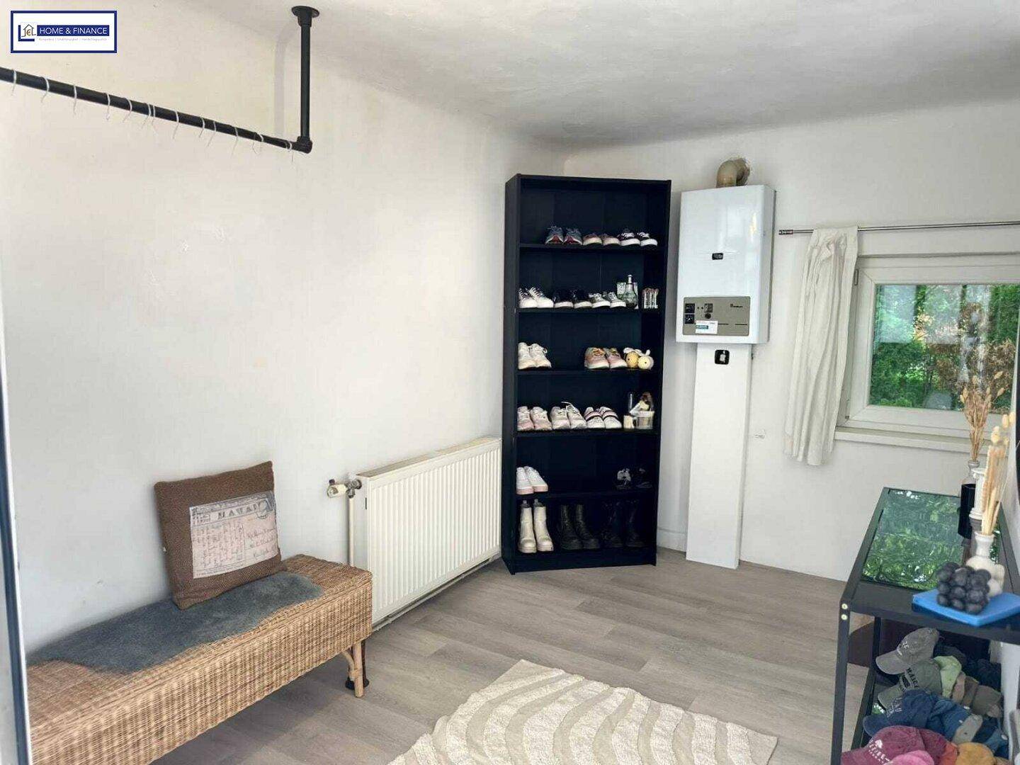 Praktischer Hauswirtschaftsraum mit Schuhregal, Heizkörper und Wandheizkessel.
