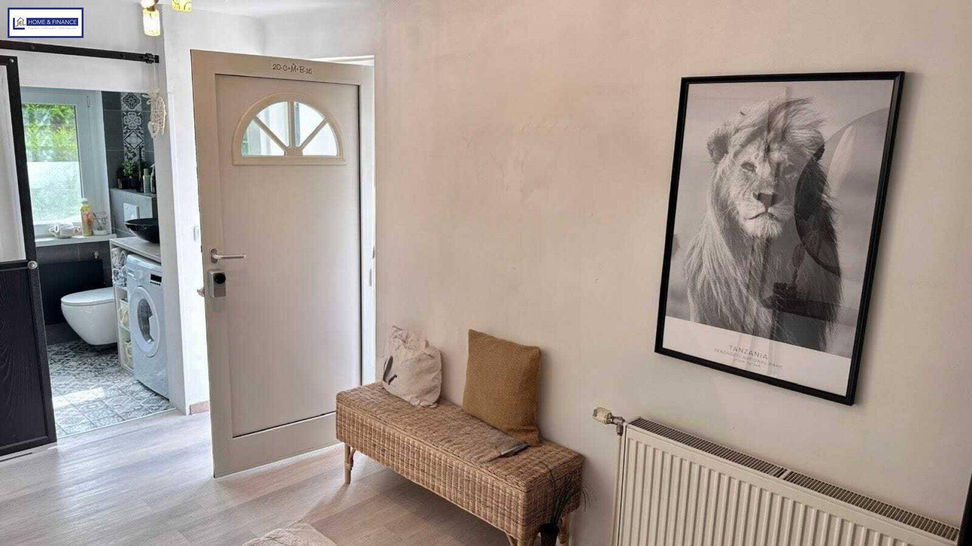 Heller Flur mit Sitzbank, Wandbild und Blick in ein angrenzendes Badezimmer.