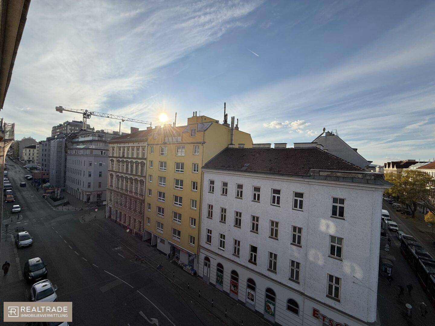 Weitblick über eine städtische Straße mit Gebäuden und einem sonnigen Himmel.