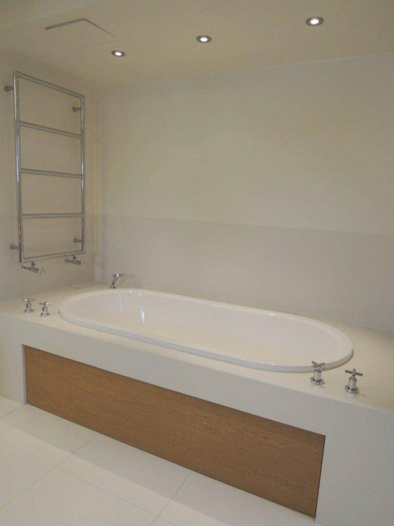 Modernes Badezimmer mit eingebauter Badewanne, beheiztem Handtuchhalter und Deckenstrahlern.
