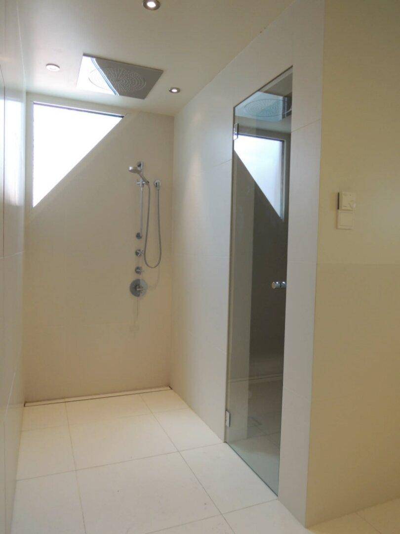 Moderne Duschkabine mit Regendusche, Handbrause und Glasabtrennung, inklusive kleinem Fenster.