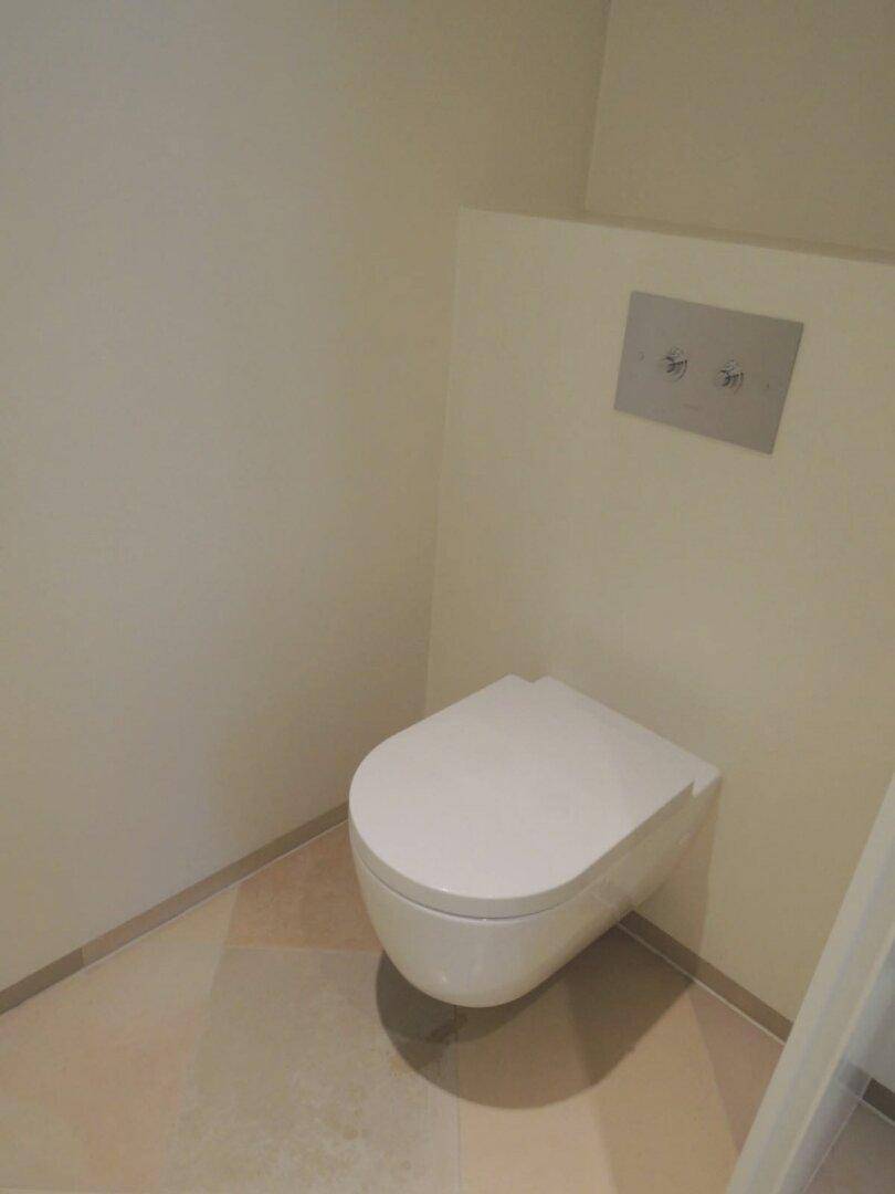 Modernes wandhängendes WC in einem schlichten, hellen Raum.
