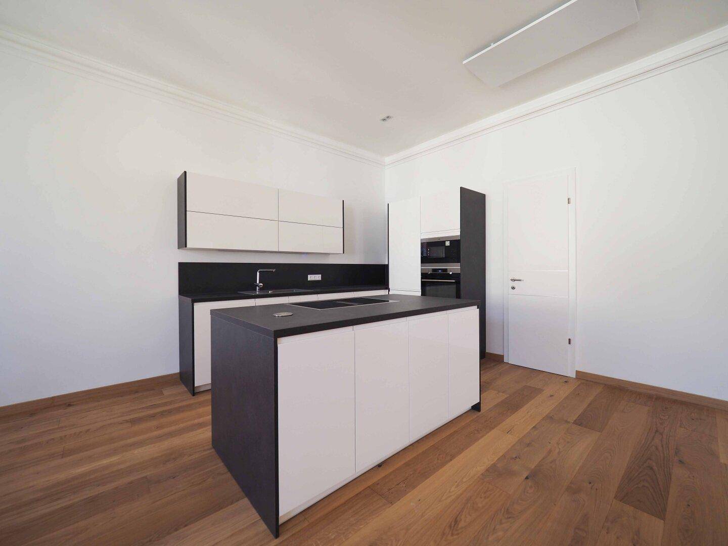 Moderne Kücheninsel mit integriertem Kochfeld und Backofen in einer hellen, offenen Küche.