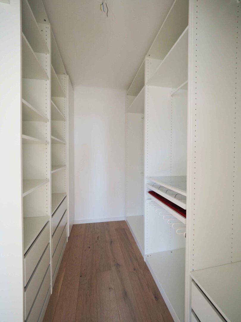 Praktischer begehbarer Kleiderschrank mit vielen Regalen und Schubladen für Stauraum.
