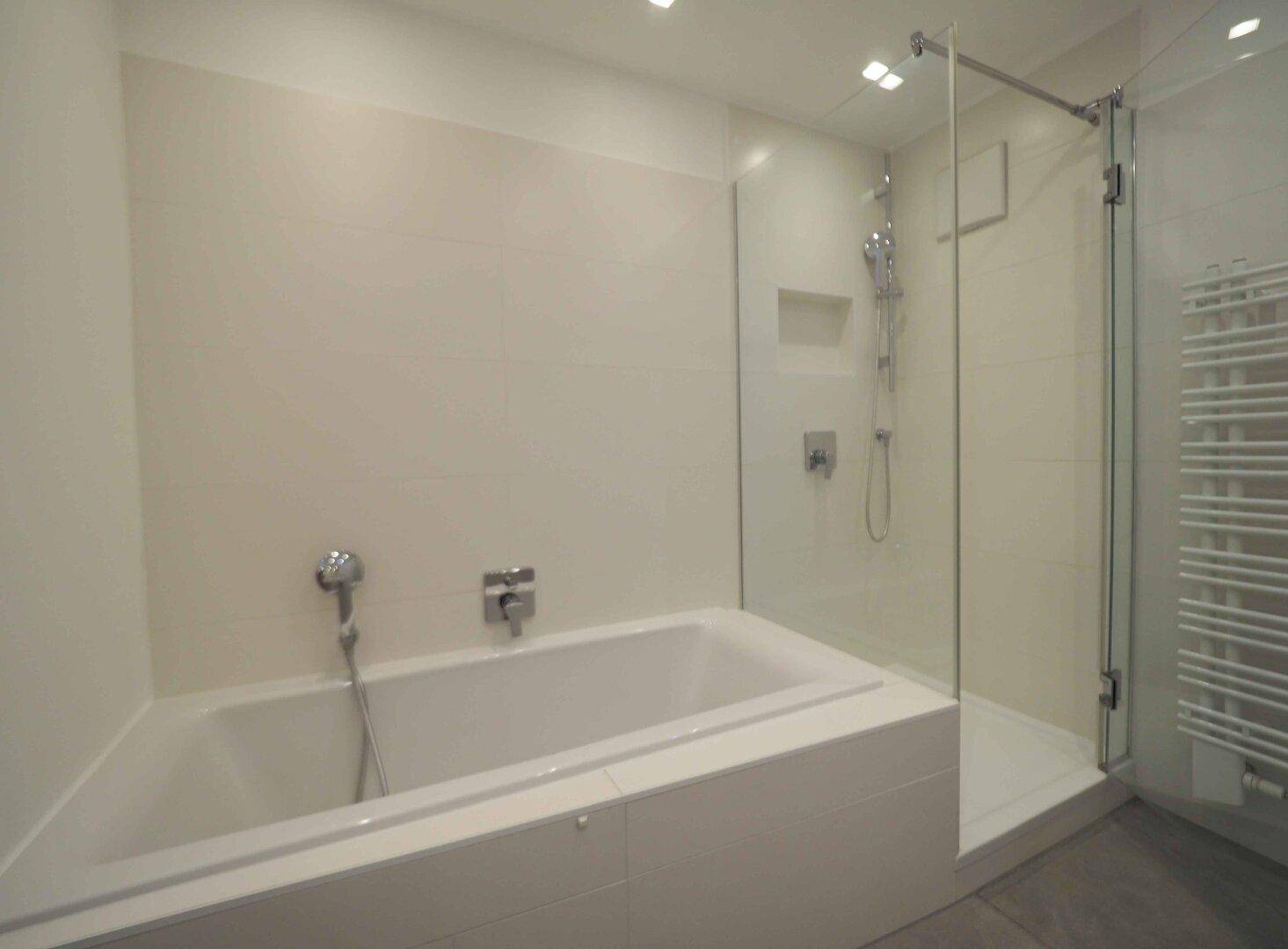 Helles Badezimmer mit Badewanne, separater Dusche und beheiztem Handtuchhalter.