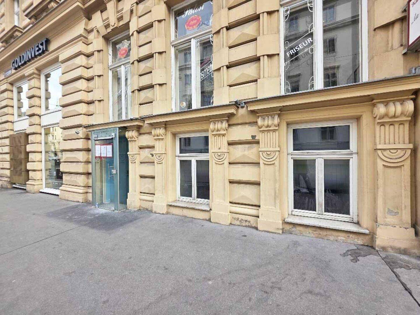Detailansicht der reich verzierten Fassade des Erdgeschosses mit Schaufenstern und einem Eingangsbereich.