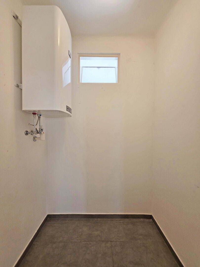 Kleiner Abstellraum mit Warmwasserboiler und einem Fenster.