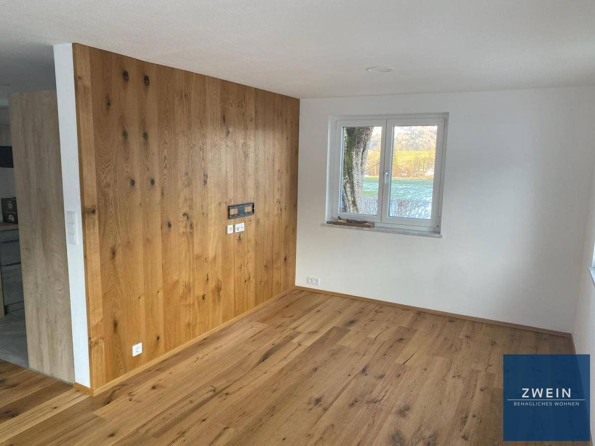 Heller Wohnbereich mit Holzwandverkleidung und Eichenparkettboden, bietet eine warme Atmosphäre.