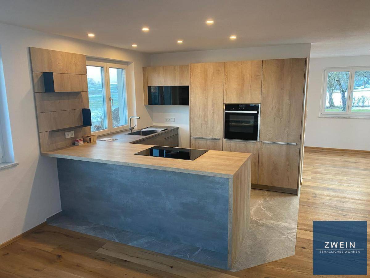 Moderne Einbauküche mit Holzfronten, Kochinsel und integrierten Geräten in hellem Raum.