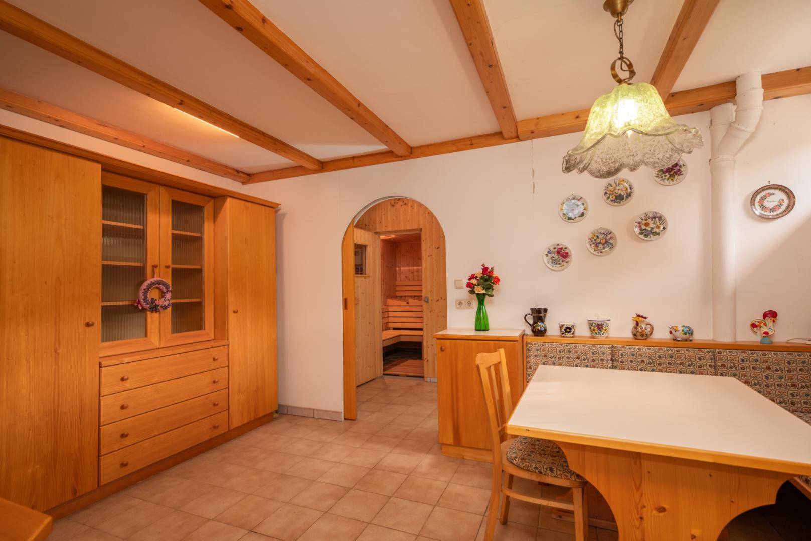 Essbereich mit Holzeinbauten, Fliesenboden und direktem Zugang zur Sauna.