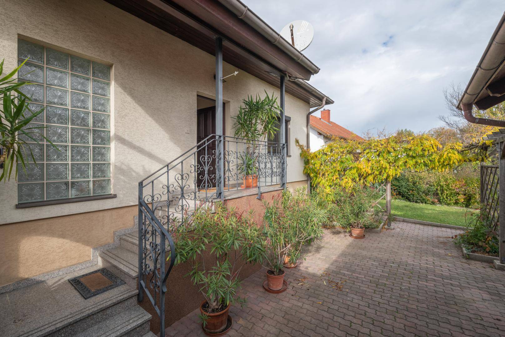 Eingangsbereich des Hauses mit Treppe, schmiedeeisernem Geländer und Glasbausteinfenster.