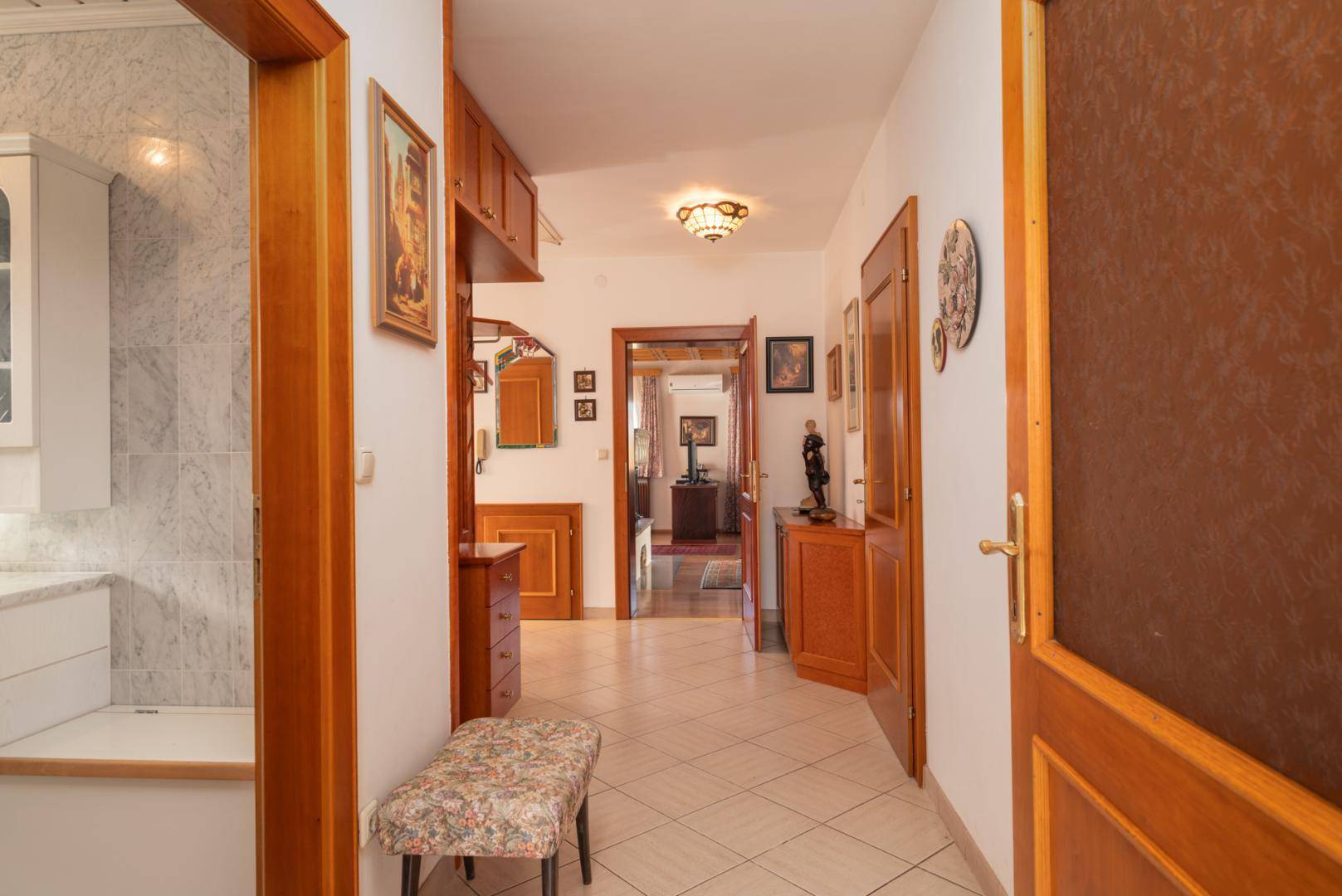 Heller Flur mit Fliesenboden, Holzmöbeln und Zugang zu weiteren Räumen.