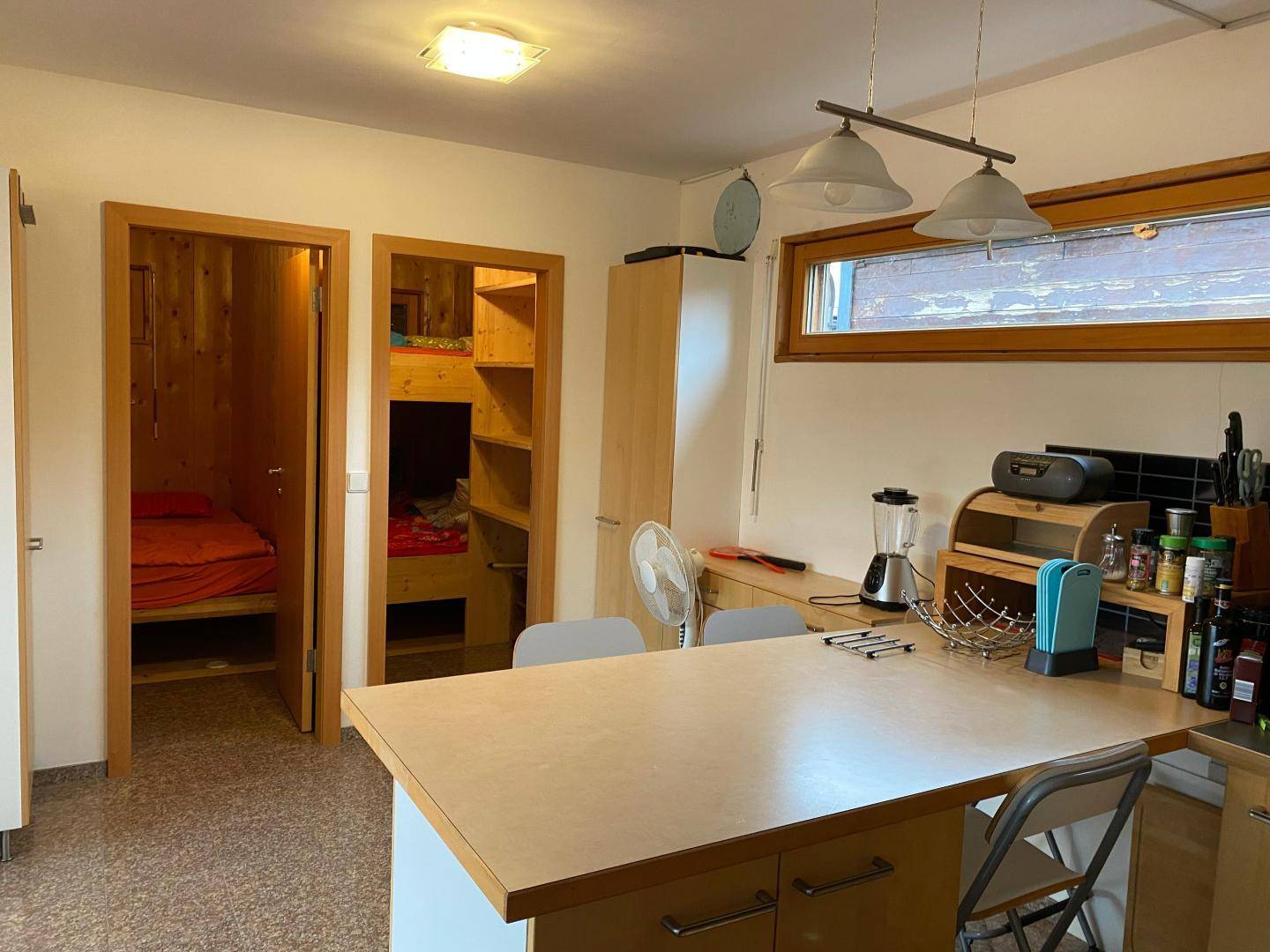 Küche mit Kochinsel und Zugang zu zwei kleinen Schlafkojen, praktisch und platzsparend.