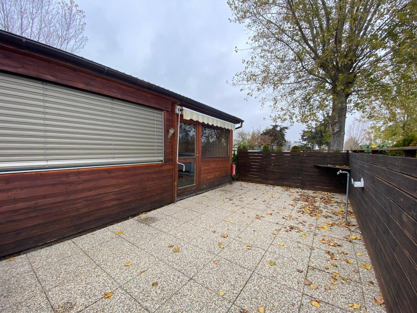 Geräumige gepflasterte Terrasse mit Holzzaun und Blick auf den Gartenbereich.