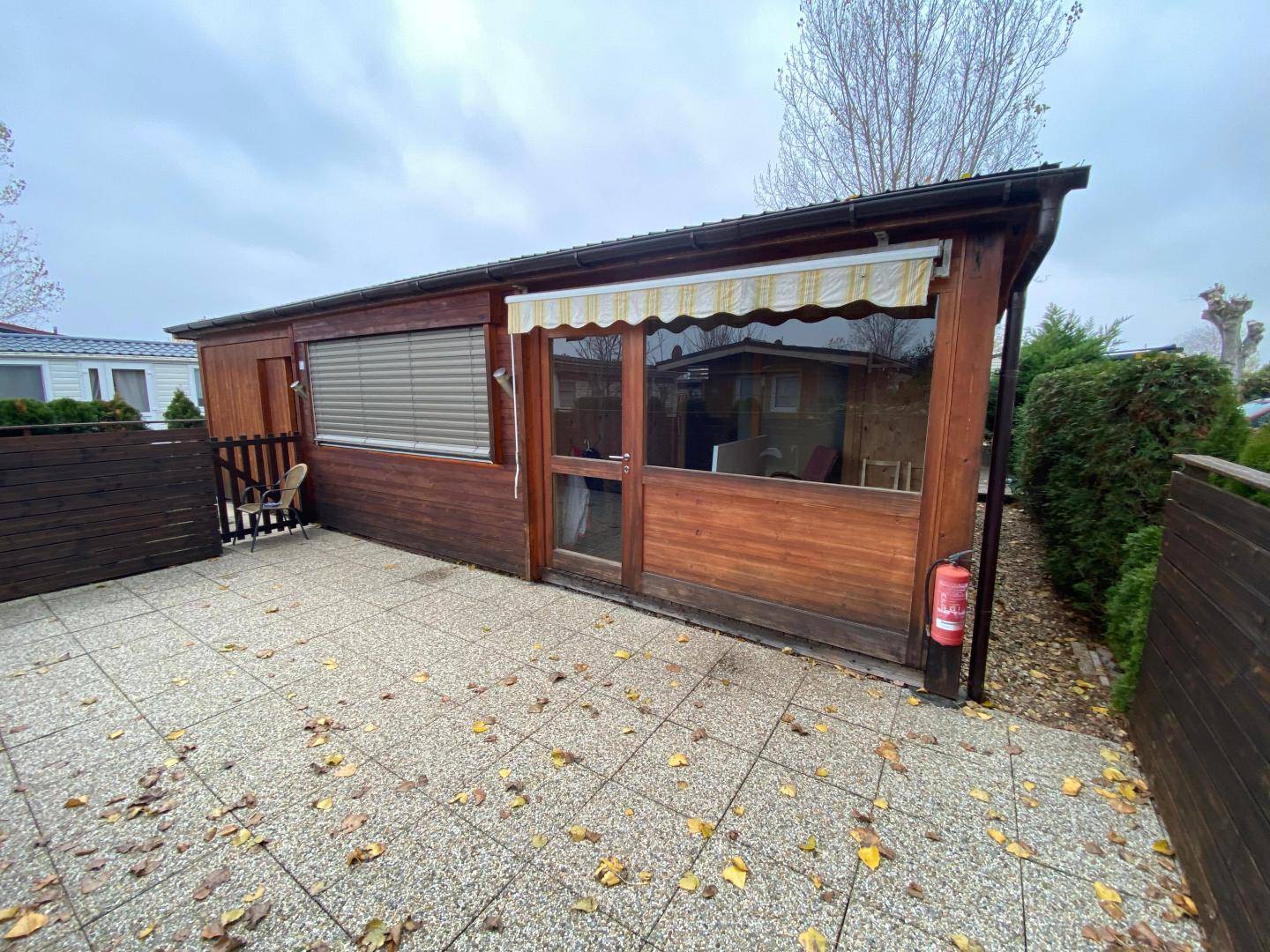 Gedeckte Terrasse mit Steinplattenboden und Holzwänden, ideal für entspannte Stunden im Freien.