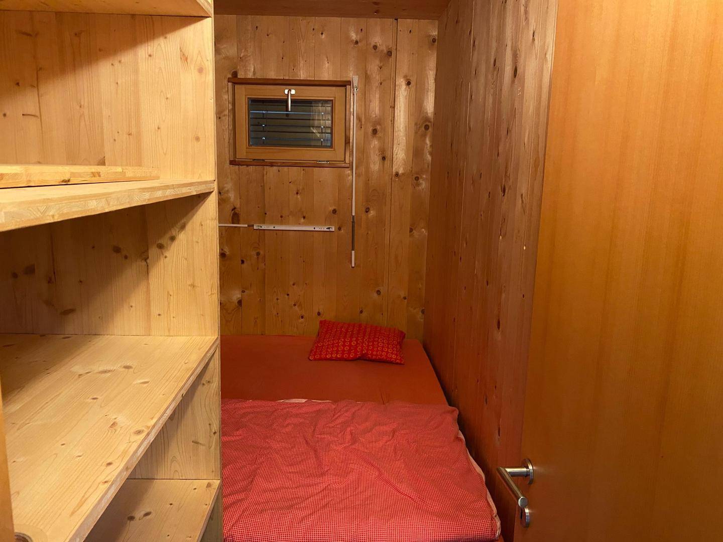 Kleine, holzvertäfelte Schlafkoje mit Einzelbett und praktischen Regalen, gemütlich eingerichtet.