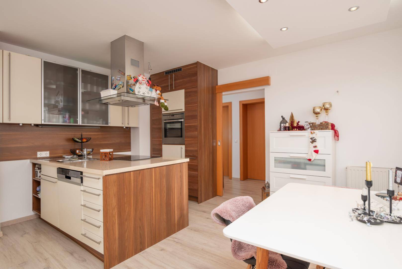 Moderne Einbauküche mit Holz- und Cremefarben, Kochinsel und integrierten Geräten.