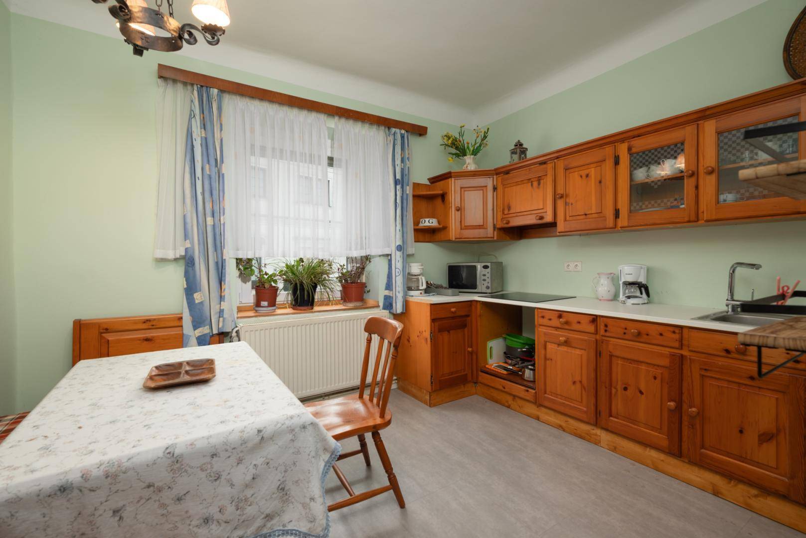 Traditionelle Küche mit Holzschränken, Esstisch und Fensterblick.